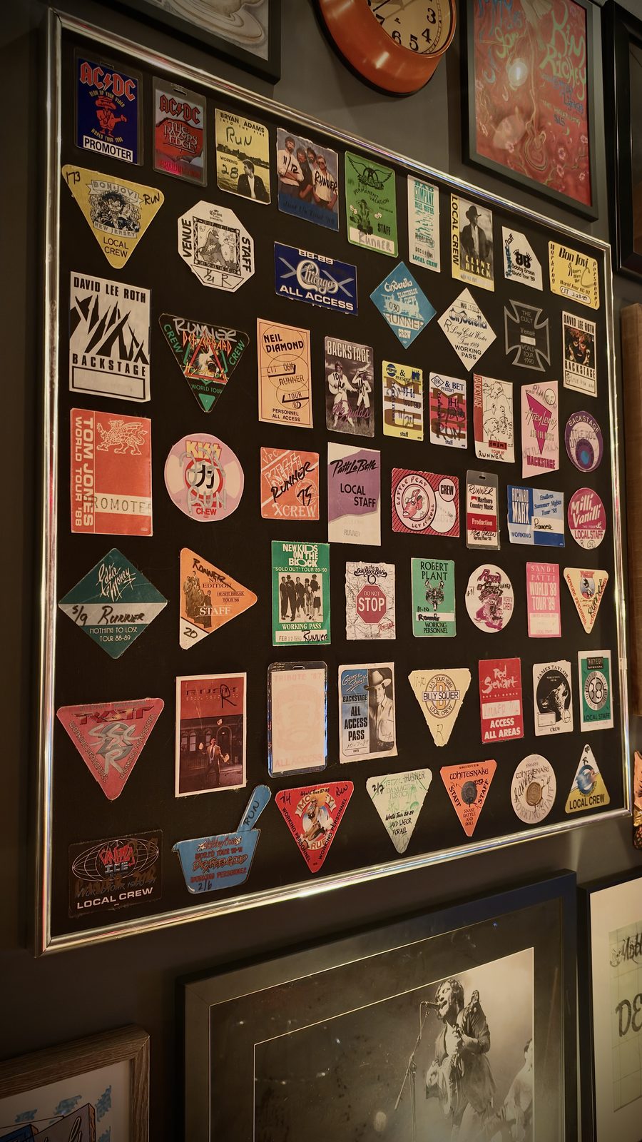 A framed wall of backstage passes and local-crew laminates from the coliseum years